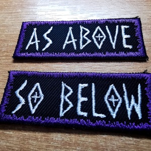 May include: Two black fabric patches with purple stitching. The top patch says "AS ABOVE" in white lettering. The bottom patch says "SO BELOW" in white lettering.