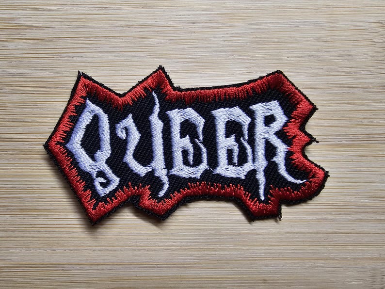 Peut inclure: Patch brod&eacute; rouge et noir avec le mot "QUBER" en lettres blanches.