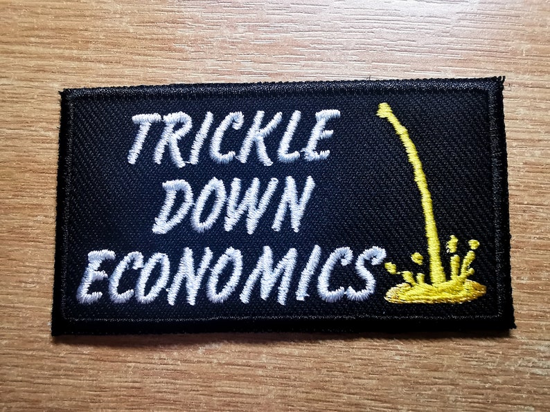 May include: Black embroidered patch with white text that reads "Trickle Down Economics" and a yellow graphic of a stream of liquid dripping from a pipe.
