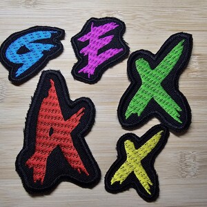 Peut inclure: Cinq patchs brodés thermocollants de différentes couleurs et designs. Les patchs sont en forme de lettres et comprennent les lettres G, E, A, X et X.