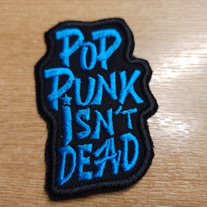 May include: A black and blue embroidered patch with the text "Pop Punk Isn't Dead".
