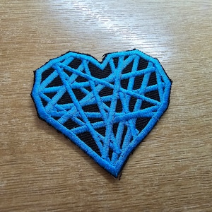 May include: A blue and black embroidered heart-shaped patch with a geometric design.