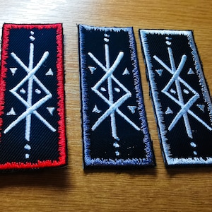 May include: Three embroidered patches with a white symbol on a black background. The patches are red, blue, and gray.