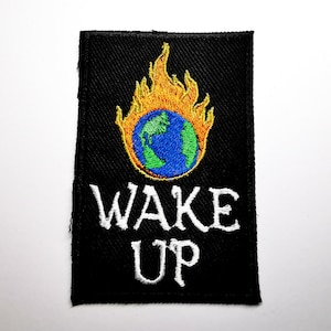 May include: Black patch with a white embroidered "WAKE UP" text and a colorful embroidered image of a globe engulfed in flames.