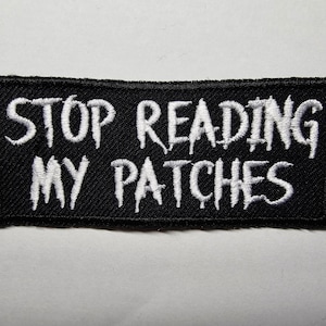May include: Black embroidered patch with white text that reads "Stop Reading My Patches".