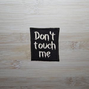 May include: Black embroidered patch with white text that reads "Don't touch me".