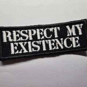 Può includere: Toppa rettangolare nera con la scritta ricamata bianca "RESPECT MY EXISTENCE". La toppa ha un bordo nero ed è progettata per essere cucita su vestiti o accessori.