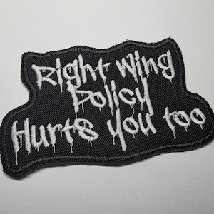 May include: Black embroidered patch with the text "Right Wing Policy Hurts You too" in white, dripping-style lettering. The patch has a unique, irregular shape and a black border.