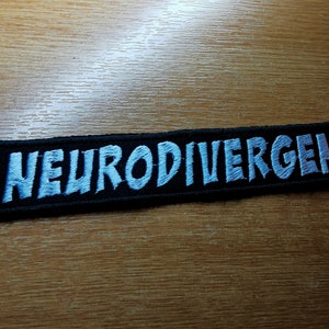 May include: Black embroidered patch with the word "Neurodivergent" in white lettering.