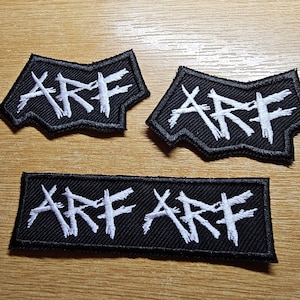 May include: Three black fabric patches with white embroidered lettering that reads "ARF" in a stylized font. The patches are in different shapes and sizes.