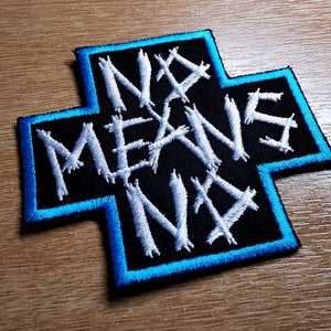 May include: A black and white embroidered patch with a blue border in the shape of a cross. The text "NO MEANS NO" is written in a stylised font.