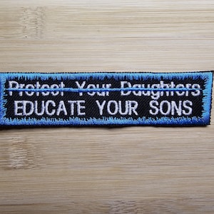 Può includere: Toppa ricamata blu e nera con testo bianco che recita "Proteggi le tue figlie Educa i tuoi figli".