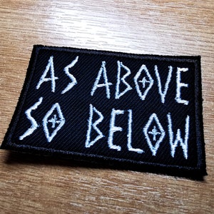 May include: Black embroidered patch with white stitching that reads "As Above So Below".