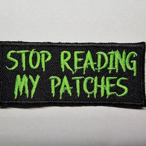 May include: Black patch with green embroidered text that reads "Stop Reading My Patches".