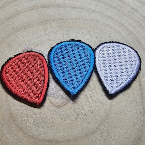 May include: Three guitar picks in the shape of a teardrop. The picks are red, blue, and white with a textured pattern.