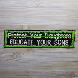 May include: Black and green embroidered patch with white text that reads "Protect Your Daughters - EDUCATE YOUR SONS".