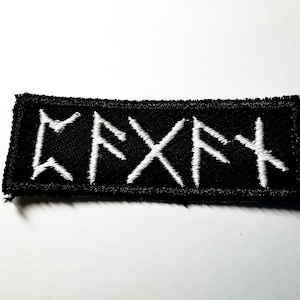 Op de afbeelding: Zwarte geborduurde patch met witte runen die "KRYPT" spellen in een gotisch lettertype.