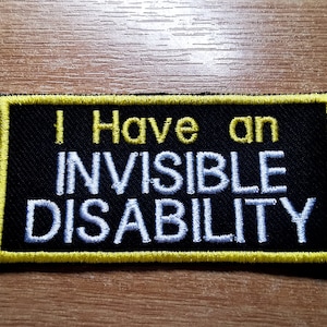 May include: Black embroidered patch with yellow stitching. The patch reads "I Have an Invisible Disability".