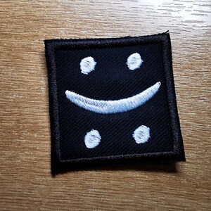May include: Black fabric patch with a white embroidered smiley face.
