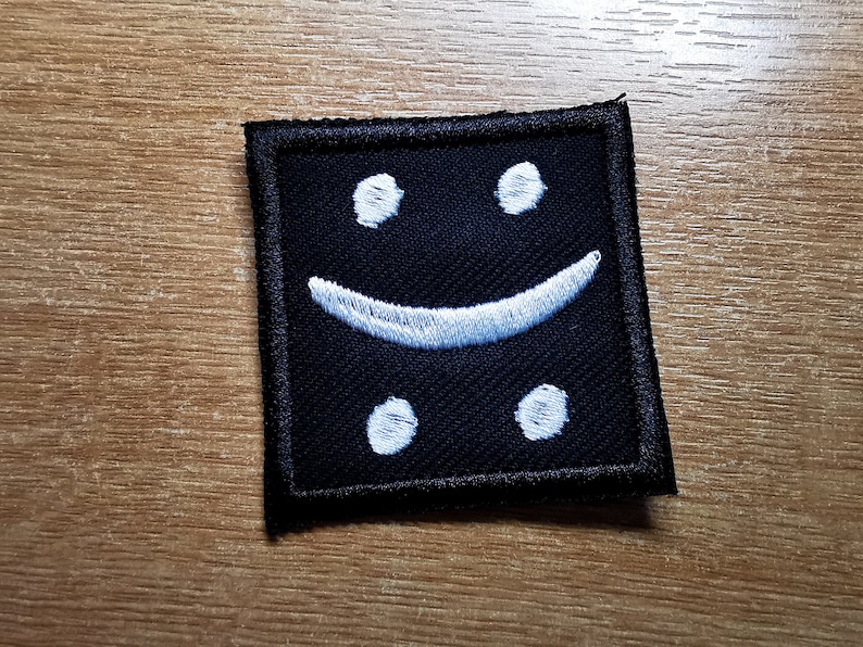 May include: Black fabric patch with a white embroidered smiley face.
