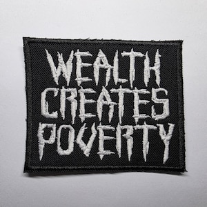 Może przedstawiać: Czarna kwadratowa naszywka z białym haftowanym tekstem „WEALTH CREATES POVERTY”. Naszywka ma czarną obwódkę i jest prawdopodobnie wykonana z tkaniny. Tekst jest pogrubioną, stylizowaną czcionką.