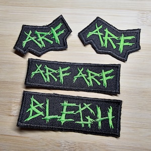 Puede incluir: Cuatro parches de tela negra con letras bordadas en verde. Los parches dicen "ARE", "ARE ARE" y "BLECH".