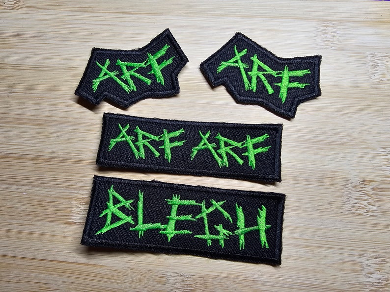 May include: Four black fabric patches with green embroidered lettering. The patches read "ARE", "ARE ARE", and "BLECH".