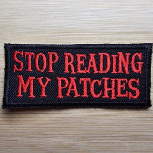May include: Black embroidered patch with red text that reads "STOP READING MY PATCHES".