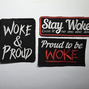 May include: Three black embroidered patches with white and red text. One patch reads "WOKE & PROUD". Another says "Stay Woke Even if no one else does". The third patch says "Proud to be WOKE".