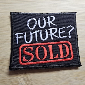 May include: Black patch with white text that reads "Our Future?" and a red rectangle with white text that reads "SOLD".