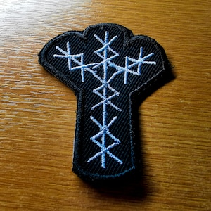 May include: A black embroidered patch with a white design of a stylized tree with three branches. The tree is surrounded by a white outline.