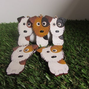 May include: Five white, brown, and black dog keychains with painted faces. The keychains are made of leather and have a furry texture.