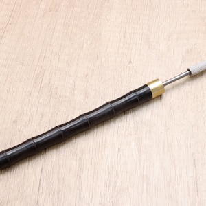 May include: A black wooden tool with a metal tip, used for leather crafting.
