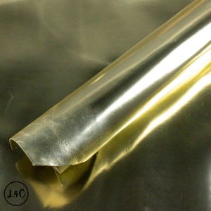 Peut inclure: Gros plan sur une feuille de cuir métallisé doré. Le cuir est roulé et la surface est brillante et réfléchissante.