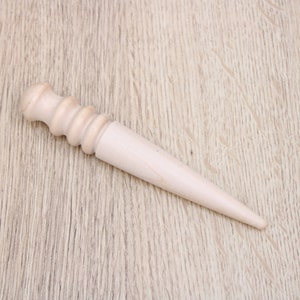 Peut inclure: Un outil de couture en cuir en bois avec une poignée arrondie et une pointe pointue.