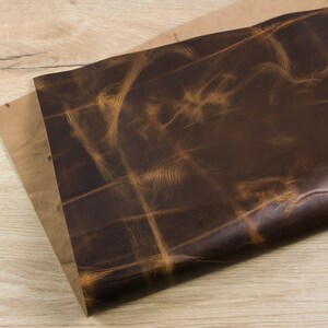 May include: A piece of brown leather with a distressed, vintage look. The leather has a natural grain pattern and a light brown colour.