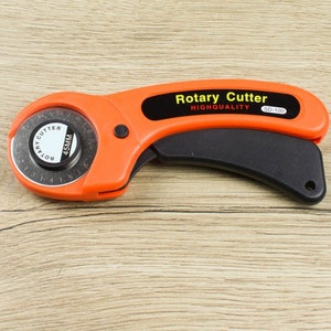 May include: Orange rotary cutter with a black handle and a 45mm blade. The cutter has a black label that reads "Rotary Cutter Highquality SD-100".