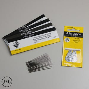 May include: An assortment of John James sewing supplies, including packs of needles and needle threaders. The needle packs are black and yellow, with the text "25 Needles". The needle threaders are in a yellow packet. The image also shows loose needles.
