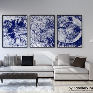 Könnte beinhalten: Drei abstrakte Kunstdrucke mit einem blauen und weißen Baumring-Design. Die Drucke sind in Schwarz gerahmt und an einer weißen Wand über einem weißen Sofa aufgehängt.