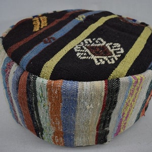 May include: A round, colourful, woven ottoman with a black and white geometric pattern on the top. The ottoman is made of a thick, durable fabric and has a striped pattern around the sides.