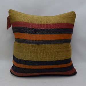 Può includere: Un cuscino a righe con uno schema di colori marrone, arancione, nero e rosso. Il cuscino è realizzato in tessuto tessuto e ha una consistenza morbida.
