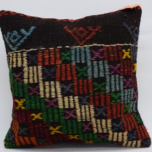 May include: A black pillow with a colorful geometric pattern. The pattern is made up of squares and rectangles in shades of red, orange, yellow, green, blue, and purple. The pillow is made of a soft, woven fabric.