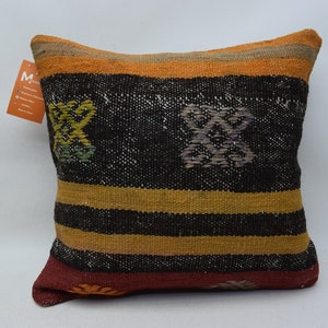May include: A black, orange and red striped cushion with a woven design. The cushion has a geometric pattern with yellow, green and purple accents.