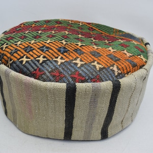 May include: A round, multi-coloured, patterned ottoman with a beige and black striped base.