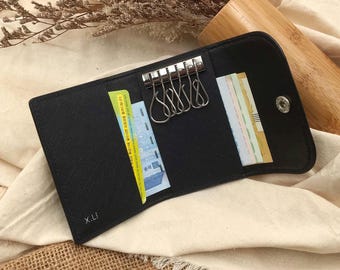 May include: Black leather key holder with a key ring and a card slot. The key holder has the initials "X.LI" embossed on the front.