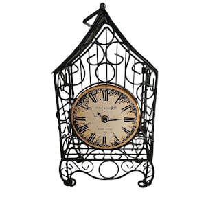 May include: Black metal decorative clock in a cage-like design. The clock face is cream-colored with black Roman numerals and the text "PEIRAT & GARNIER SAINT CROIX". The clock has a vintage, antique aesthetic.