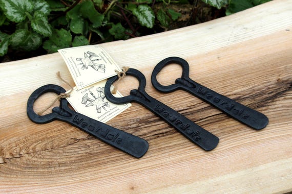 A real blacksmith hammers each one by hand and burns your name or message into it — the kind of bottle opener that lives on a wall, not in a drawer.
