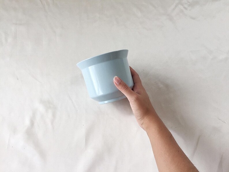 Peut inclure: Un pot de fleurs en c&eacute;ramique bleu clair. Le pot est rond avec un bord l&eacute;g&egrave;rement &eacute;vas&eacute;.