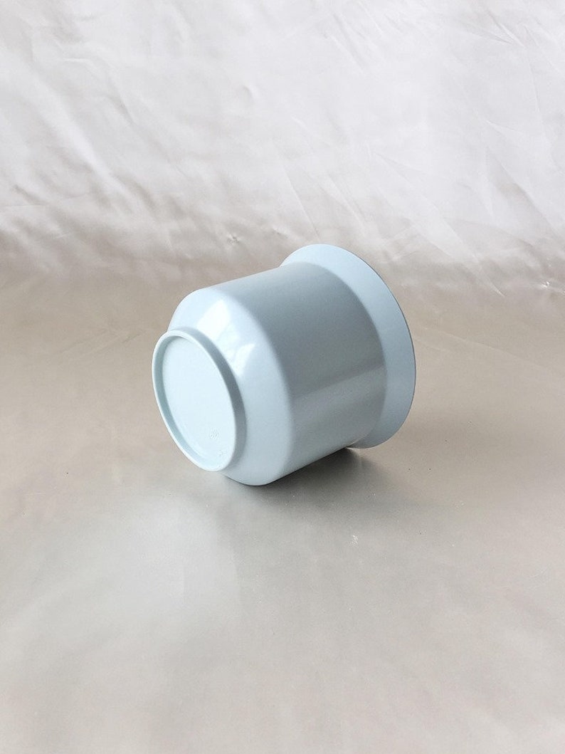Peut inclure: Un pot de fleurs en c&eacute;ramique bleu clair. Le pot est rond et a une finition lisse et brillante.