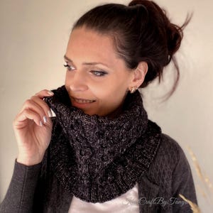 Könnte beinhalten: Ein schwarz-weißer Strick-Kragenpullover mit Zopfmuster. Der Schal wird von einer Person mit braunen Haaren getragen.